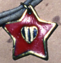 metal enamel pendant of a red star with a black heart and white stripes.png