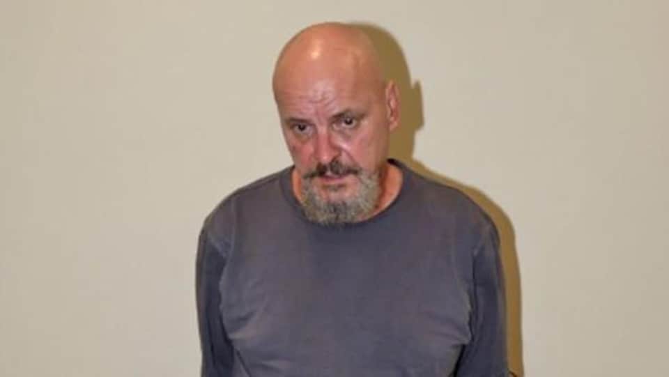 Une photo de la police montre le prévenu avec les mains attachées derrière le dos.