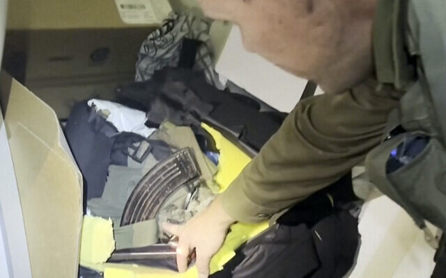 In this image taken from a video released by the Israeli Defense Forces, Wednesday, Nov. 15, 2023, Lt. Col. Jonathan Conricus, an Israeli military spokesman, points to a cache of weapons the IDF says were found in an MRI center at the al-Shifa hospital in Gaza City. (Israel Defense Forces via AP)