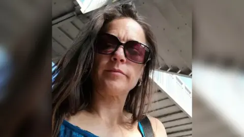 Hampshire police Joanne Sheen has long, dark brown hair and wears sunglasses and a lacey blue, sleeveless top.