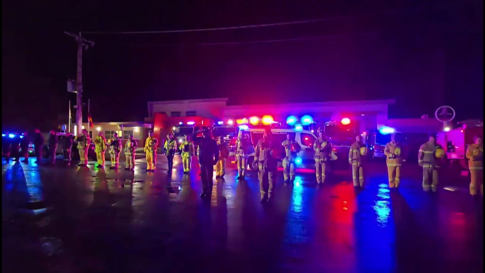 A line of firefighters and other emergency personell observing two minutes of silence. 