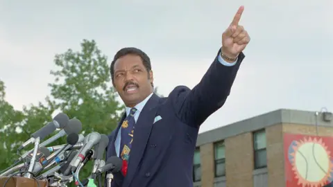Bettmann Archive/Getty Images Jesse Jackson points into the air. He is wearing a blue suit. 