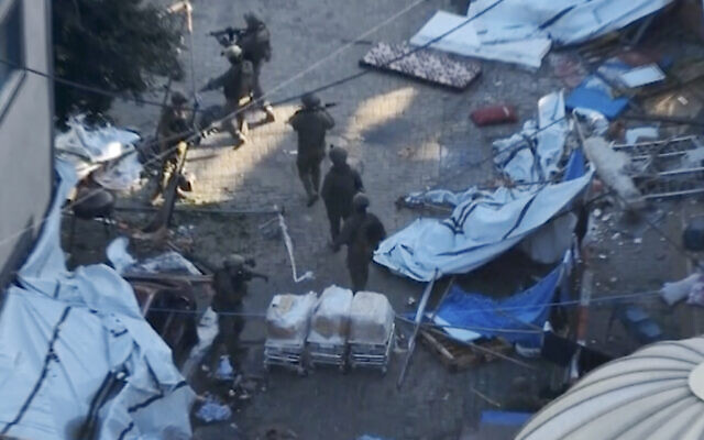 In this image taken from a video released by the Israeli Defense Forces on Tuesday, Nov. 15, 2023, Israeli soldiers walk in the area of Al-Shifa hospital in Gaza City. (Israel Defense Forces via AP)