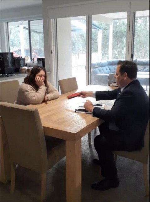 Erin Patterson sits at her table across from a police officer.