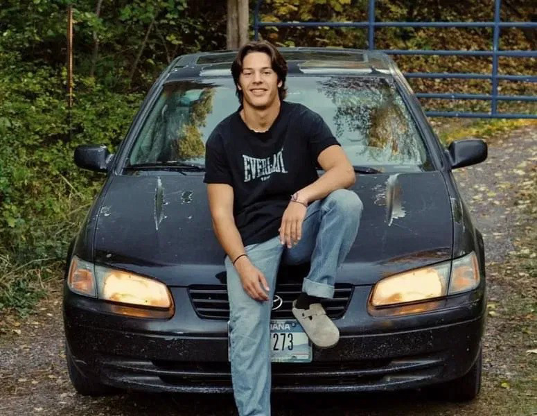 Josiah Kilman sitting on the hood of a late-model Toyota.