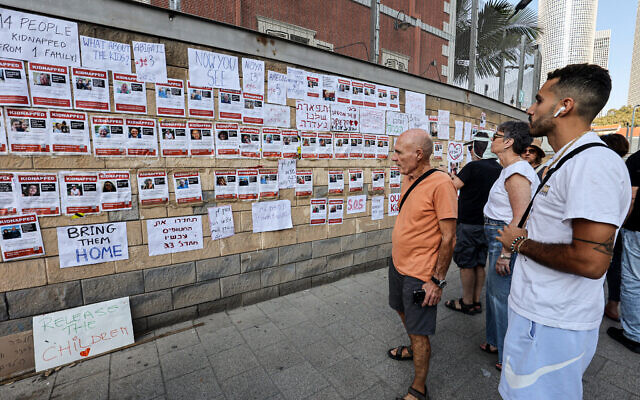Supporters and family members of Israeli hostages look at images of the hostages plastered on a wall during a rally outside of the Israeli military base HaKirya in central Tel Aviv on October 14, 2023. (Gil Cohen-Magen/AFP) Supporters and family members of Israeli hostages look at images of the hostages plastered on a wall during a rally outside of the Israeli military base HaKirya in central Tel Aviv on October 14, 2023. (Gil Cohen-Magen/AFP)